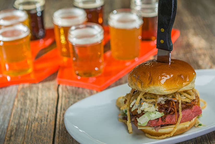 a burger with a beer sampler behind it