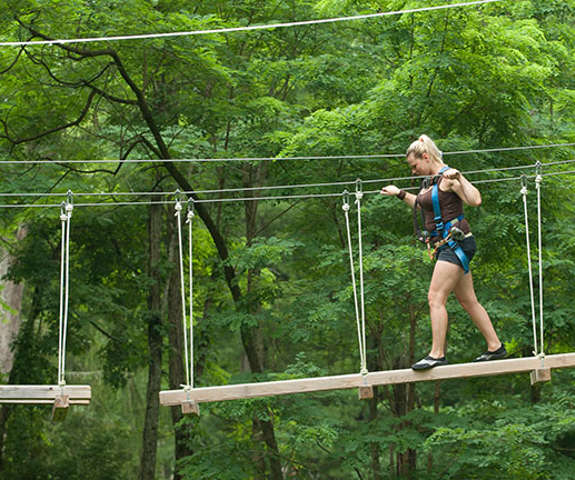 woman walking across ropes course in Gorilla Grove Treetop Adventure.