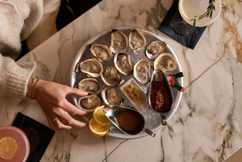 A woman selecting an oyster to eat. 