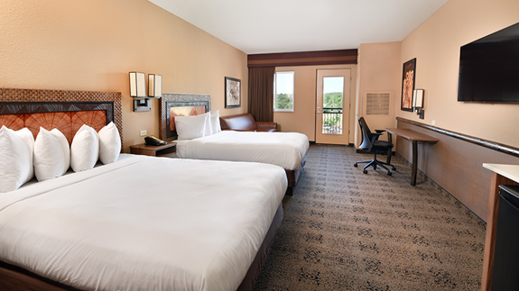 an overview of inside the Two Bedroom Suite. Consists of beds, desk, microwave, and tv.