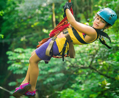 A little girl traversing the Gorilla Grove Treetop Adventure Ropes Course.