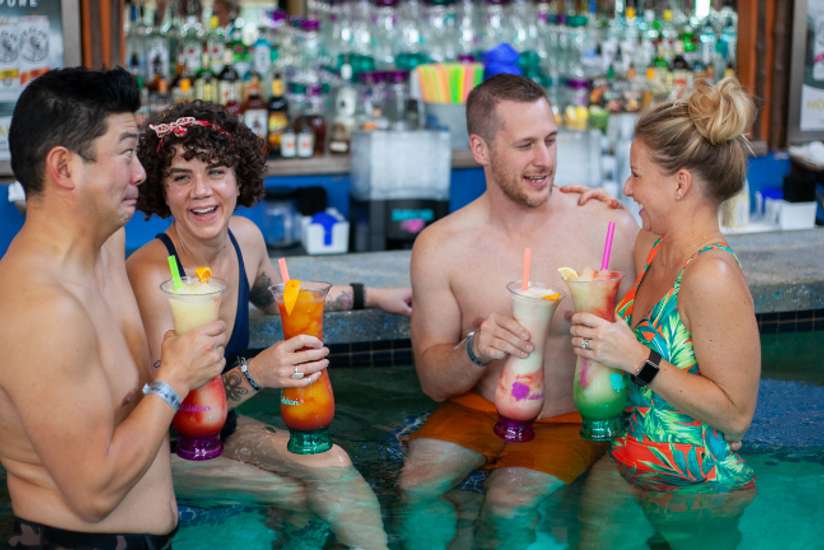 Two couples in the the indoor swim-up bar enjoying monster cocktails.