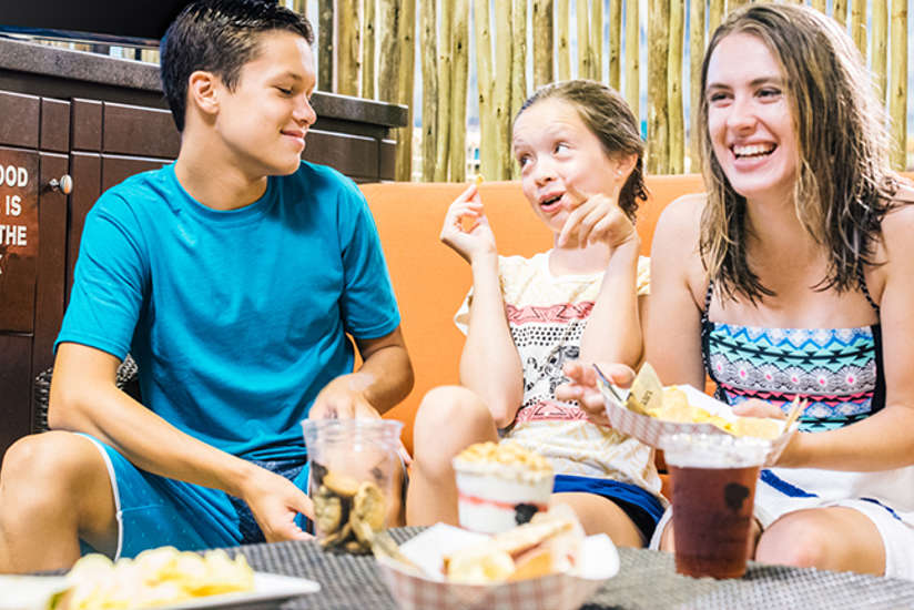 some kids munching on some food in a cabana in the waterpark