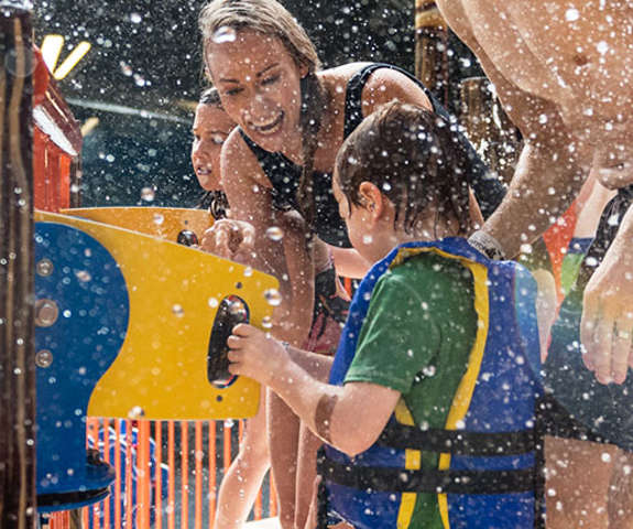 A family laughing as they splash each other with water.
