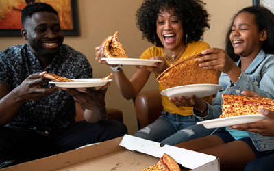 A family eating room service cheese pizza.