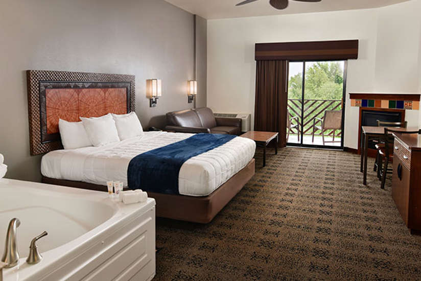 An interior of a Kalahari Resorts hotel room named the King Whirlpool featuring a king bed and balcony, and hot tub.