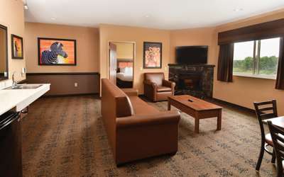 an overview of inside the 3 Bedroom Family Suite. Consists of a kitchen area, fireplace, a dining area, a couch, and a table.