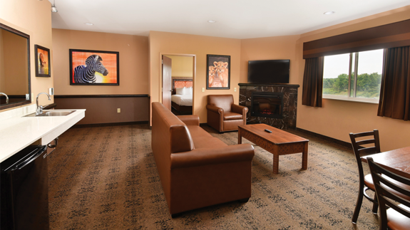 an overview of inside the 3 Bedroom Family Suite. Consists of a kitchen area, fireplace, a dining area, a couch, and a table.