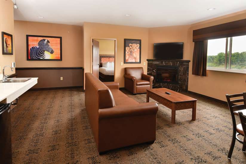 an overview of inside the 3 Bedroom Family Suite. Consists of a kitchen area, fireplace, a dining area, a couch, and a table.