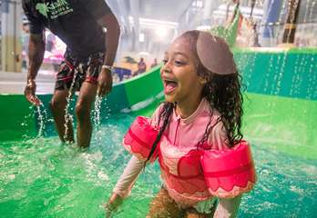 A little girl laughs as she splashes in a water play area