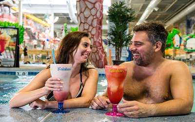 a couple smiling and drinking their huge drinks in the pool bar