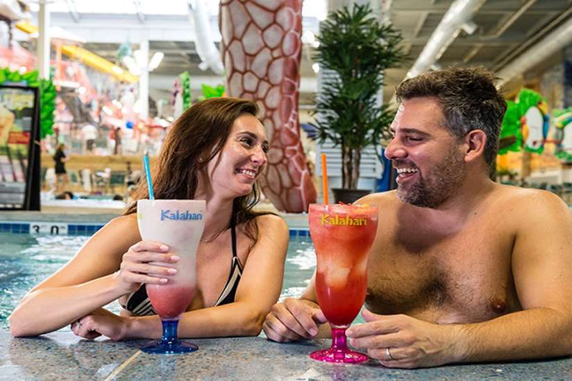 a couple smiling and drinking their huge drinks in the pool bar