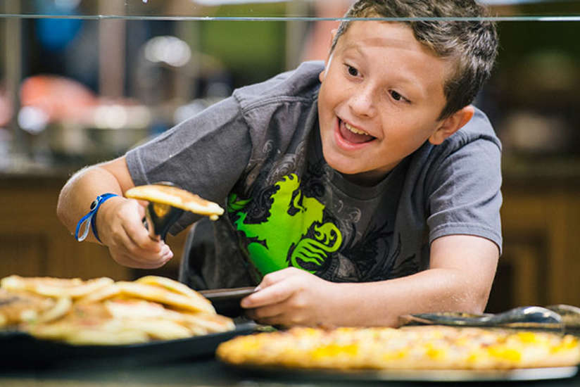a boy grabbing a pancake off a platter
