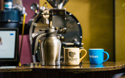 a coffee pot next to two cups with Kalahari logos on them