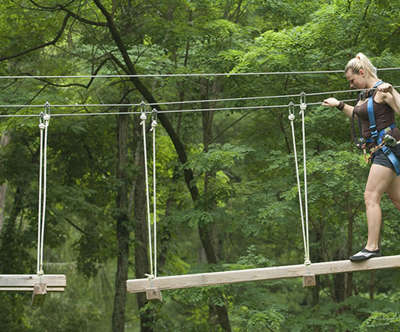 woman walking across ropes course in Gorilla Grove Treetop Adventure.