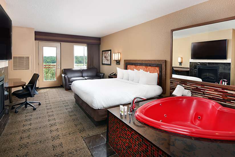an overview of inside the Honeymoon Suite. Consists of bed, desk, tv, mirror, and heart-shaped tub.
