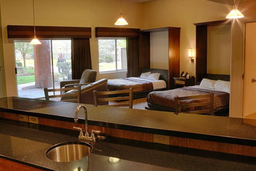 Overview of the Hospitality Suite. Consists of a kitchen area, fireplace, tv, two beds, and living area