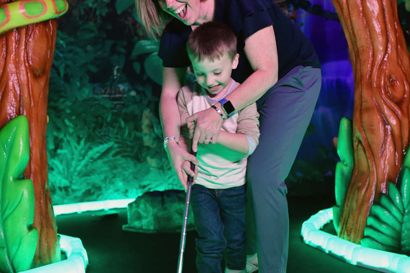 Mom and son playing indoor mini golf
